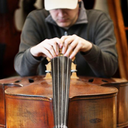 Photo of instrument repair person setting up bridge on a bass
